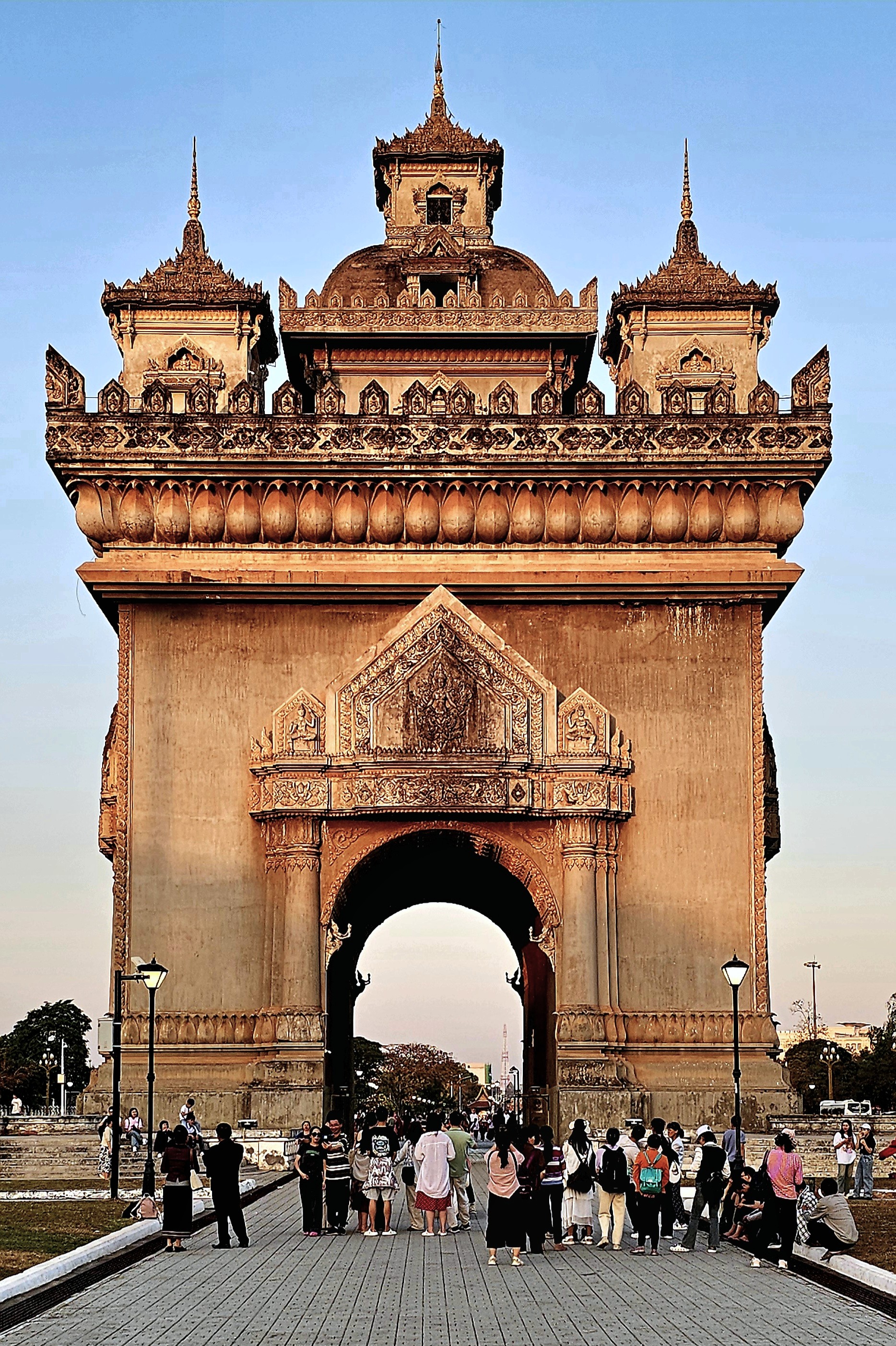 The Patuxay Monument in Vientiane, Laos, showcasing intricate architectural details and a busy scene of visitors gathering in front of the landmark.