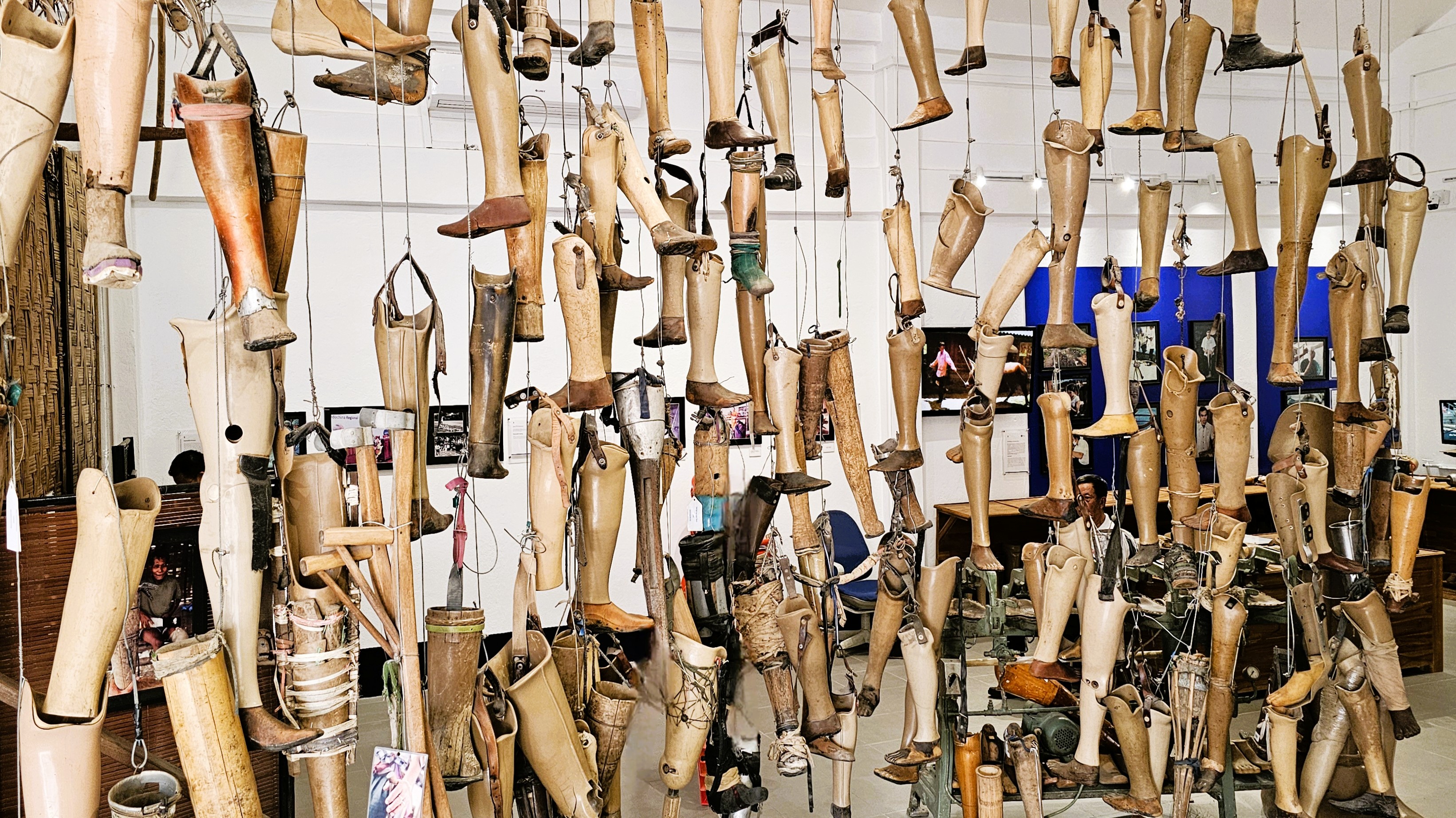 Display of prosthetic limbs hanging in an exhibit, symbolizing the impact of unexploded ordnance in Laos.