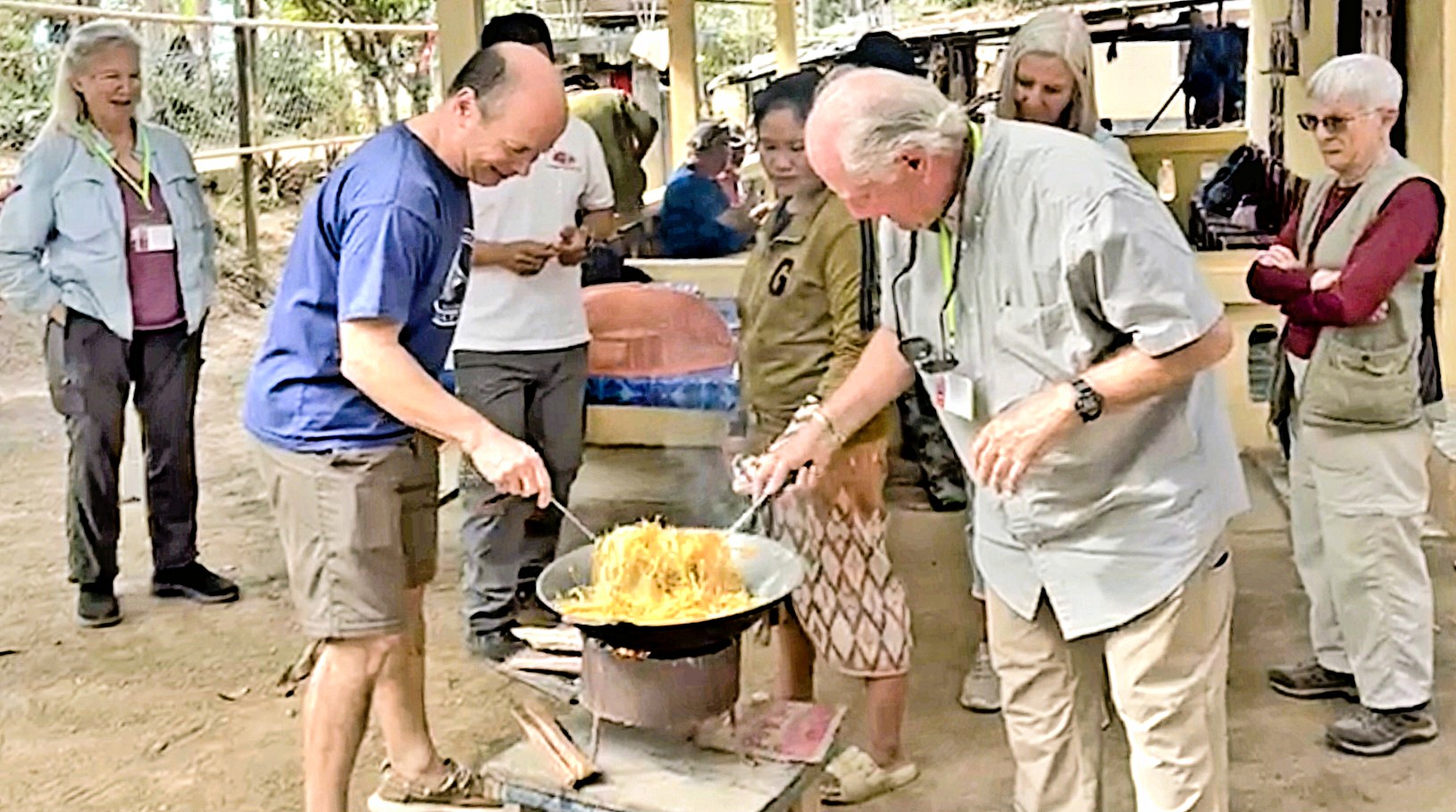 Tourists engage in cooking while learning about local cuisine in a village setting.