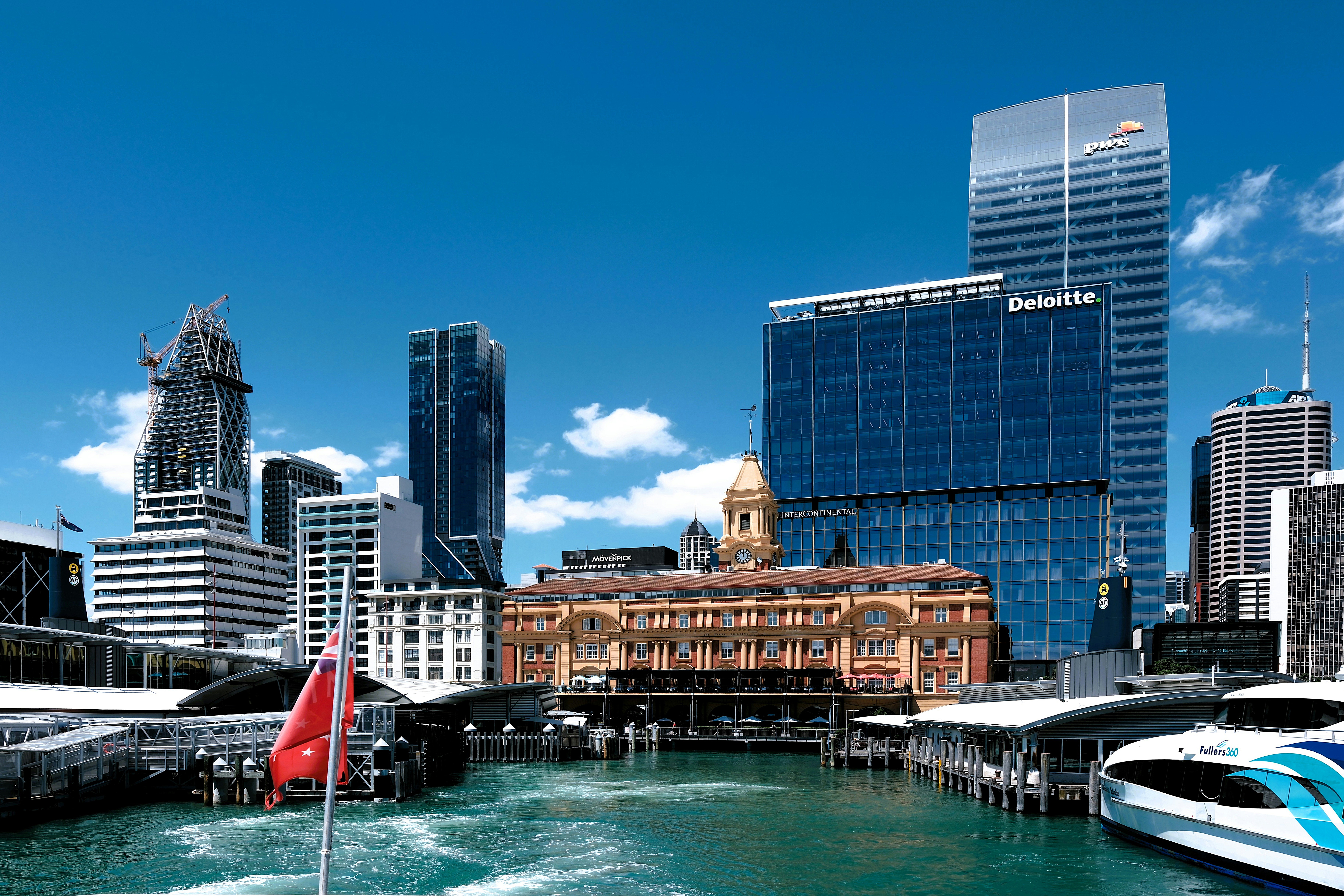 City skyline featuring modern skyscrapers and historic architecture along a waterfront with boats.